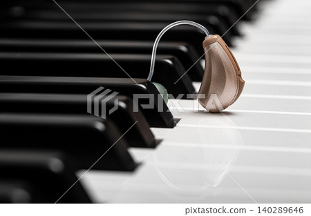 Close-up hearing aid on piano keys. Treatment of deafness. Hearing solution, hear all the variety of sounds in the world Close-up hearing aid on piano keys. Treatment of deafness. Hearing solution, hear all the variety of sounds in the world 140289646
