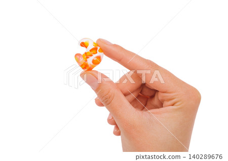 Isolated on white earplug in female hand. Personally molded earplugs close-up. Part of the set 140289676