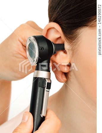 Hearing exam. Otoscope and ear of a child close-up isolated on white. Hearing test in a clinic. 140290072