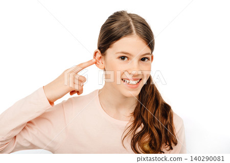 Pretty girl point on her ear and smiling. My hearing is perfect. Child hearing exam and hearing treatment concept Pretty girl point on her ear and smiling. My hearing is perfect. Child hearing exam and hearing treatment concept 140290081