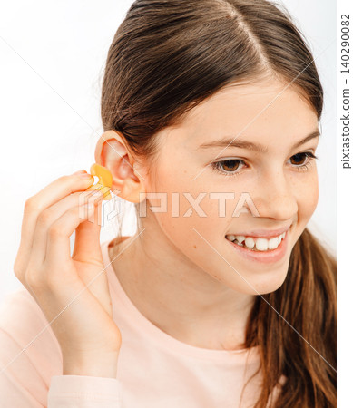 Individual earplugs for children. Girl holding individual ear plugs near ear, closeup Individual earplugs for children. Girl holding individual ear plugs near ear, closeup 140290082