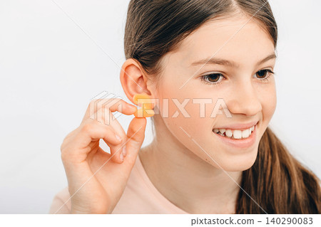 Individual earplugs for children. Girl holding individual earplug near ear, close-up. 140290083