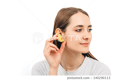 Individual earplugs for women. Woman holding customized earplug near the ear, on white background 140290113