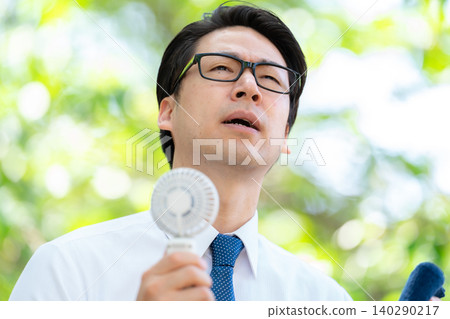 Businessman, extreme heat, handheld fan Businessman, extreme heat, handheld fan 140290217