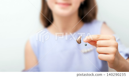 Hearing aid in hand of a teenage girl patient, close-up. Selection of hearing aid for a child. Hearing concept 140290235