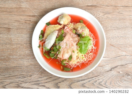 Chinese yellow egg noodles with fish ball and pork dumpling in red soup on plate Chinese yellow egg noodles with fish ball and pork dumpling in red soup on plate 140290282