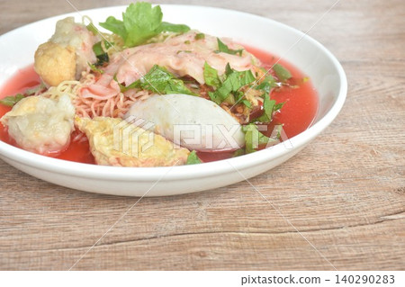 Chinese yellow egg noodles with fish ball and pork dumpling in red soup on plate Chinese yellow egg noodles with fish ball and pork dumpling in red soup on plate 140290283