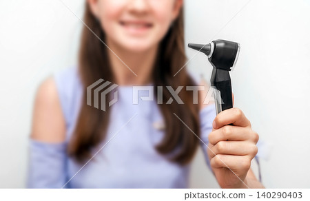 Otoscope in hand of a teenage girl, close-up. Concept ear treatment and hearing exam to a children. Soft focus Otoscope in hand of a teenage girl, close-up. Concept ear treatment and hearing exam to a children. Soft focus 140290403
