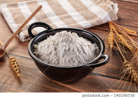 Wheat Flour in Black Bowl with Wheat Ears and Wooden Spoon on Rustic Table Wheat Flour in Black Bowl with Wheat Ears and Wooden Spoon on Rustic Table 140290530