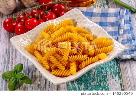 Uncooked fusilli pasta in white bowl with fresh ingredients Uncooked fusilli pasta in white bowl with fresh ingredients 140290540