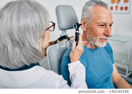 Senior man during ear test with audiologist at audiology. Diagnosis of impairment and hearing testing to senior people, otoscopy Senior man during ear test with audiologist at audiology. Diagnosis of impairment and hearing testing to senior people, otoscopy 140290586