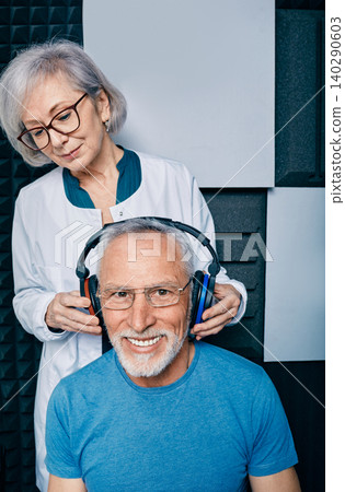 Audiometry, pure tone audiogram test. Audiologist doing hearing exam to mature man in soundproof audiometric cabin Audiometry, pure tone audiogram test. Audiologist doing hearing exam to mature man in soundproof audiometric cabin 140290603