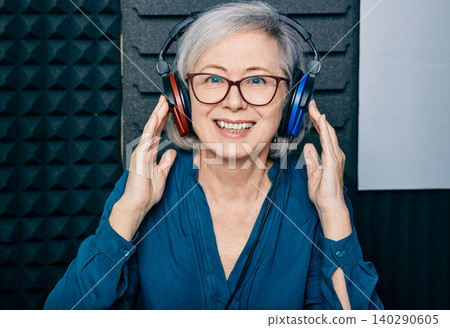 Hearing loss treatment. Positive mature woman wearing audiometry headphones while hearing test and audiogram in special audio room Hearing loss treatment. Positive mature woman wearing audiometry headphones while hearing test and audiogram in special audio room 140290605