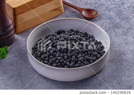 Raw black beans in ceramic bowl on gray stone with wooden spoon Raw black beans in ceramic bowl on gray stone with wooden spoon 140290626
