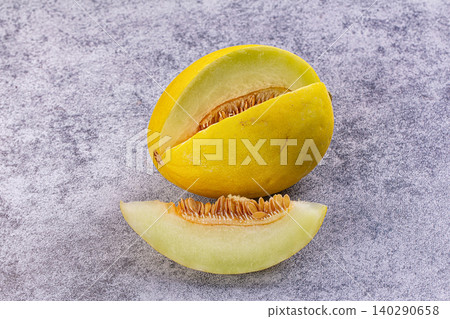 Yellow melon with slice on gray stone background 140290658
