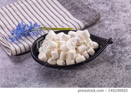 White marshmallows in black leaf shaped bowl with blue flowers 140290685