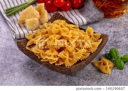 Uncooked Farfalle Pasta in Wooden Bowl with Ingredients 140290687