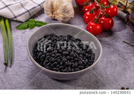 Black beans in gray bowl with fresh vegetables and herbs on stone surface Black beans in gray bowl with fresh vegetables and herbs on stone surface 140290691