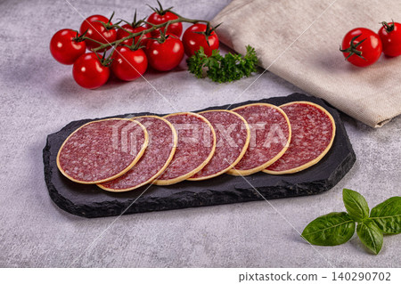 Sliced salami on slate board with fresh tomatoes and basil Sliced salami on slate board with fresh tomatoes and basil 140290702