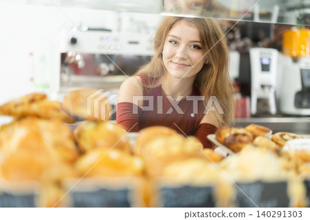 Woman seller putting fresh pastries on plate in cafe bakery Woman seller putting fresh pastries on plate in cafe bakery 140291303