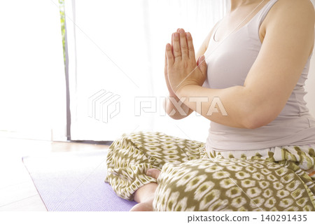 一位女性在冥想中平靜思緒時,雙手自然垂落。 一位女性在冥想中平靜思緒時,雙手自然垂落。 140291435