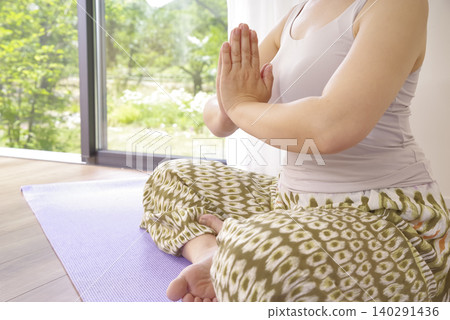 一位女性在冥想中平靜思緒時,雙手自然垂落。 一位女性在冥想中平靜思緒時,雙手自然垂落。 140291436