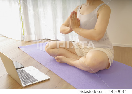 在家觀看瑜伽影片並練習瑜伽的女性。 在家觀看瑜伽影片並練習瑜伽的女性。 140291441