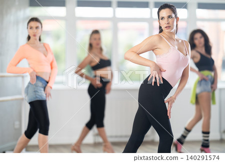 During lesson, girl learn to move and perform dance in heels with women companions During lesson, girl learn to move and perform dance in heels with women companions 140291574