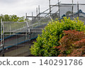 Scaffolding and netting for repairing the roof and walls of a house. 140291786