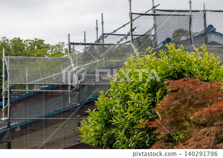 Scaffolding and netting for repairing the roof and walls of a house. Scaffolding and netting for repairing the roof and walls of a house. 140291786