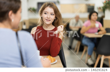 Girl in cafe sits near girl companion; has nice conversation and discusses news of day Girl in cafe sits near girl companion; has nice conversation and discusses news of day 140291824