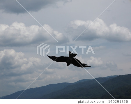 風箏在空中翱翔,遠處是連綿的山脈。 風箏在空中翱翔,遠處是連綿的山脈。 140291856