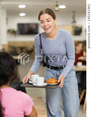 Cafe girl visitor puts tray on table and joins group of friends Cafe girl visitor puts tray on table and joins group of friends 140291962
