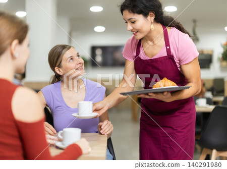 Young female waitress serves coffee and croissant Young female waitress serves coffee and croissant 140291980