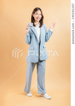 Happy young Asian businesswoman holding credit cards and a confident smile isolated on white studio background. Happy young Asian businesswoman holding credit cards and a confident smile isolated on white studio background. 140292287