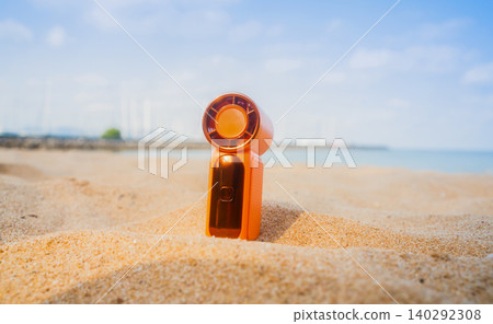 Portable handy fan on the beach and the background is the sea and the sky in summer. Portable handy fan on the beach and the background is the sea and the sky in summer. 140292308
