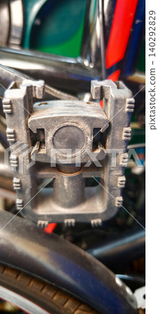 Close-up view of a folding bike pedal showcasing intricate design and durable materials, mounted on a bicycle frame with visible components in the background Close-up view of a folding bike pedal showcasing intricate design and durable materials, mounted on a bicycle frame with visible components in the background 140292829