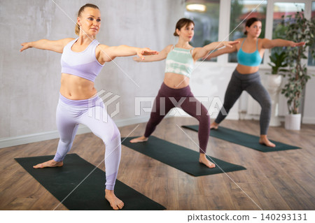 Young woman practicing stretching during group yoga class Young woman practicing stretching during group yoga class 140293131