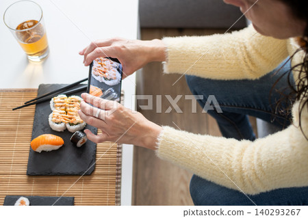 Person Eating Assorted Sushi with Chopsticks at Home 140293267