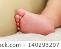 A close-up of a baby's tiny feet resting on a soft cloth. 140293297