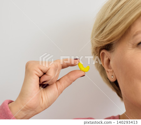 Personally molded yellow earplugs for mature woman ears, close-up. Individual earplugs for noisy places Personally molded yellow earplugs for mature woman ears, close-up. Individual earplugs for noisy places 140293413