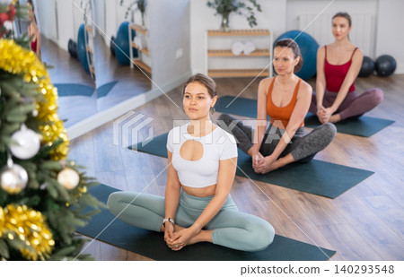 Girl teacher conducts yoga lesson for girls and performs butterfly asana in New Year atmosphere Girl teacher conducts yoga lesson for girls and performs butterfly asana in New Year atmosphere 140293548