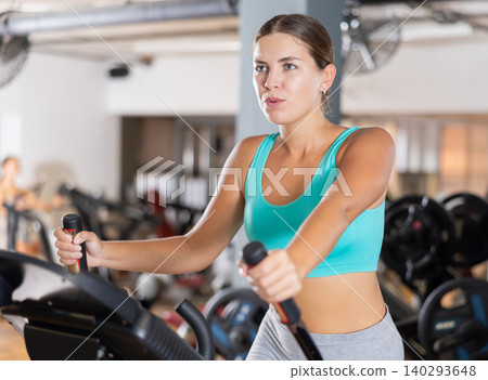 Young woman working out on elliptical machine 140293648
