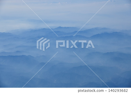 The view of the stunning landscape with mountains and clouds from the airplane window. Aerial view of the natural scene, mountain range. Travel and landscape scene. Travel and nature concept.  140293682
