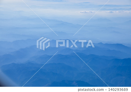 The view of the stunning landscape with mountains and clouds from the airplane window. Aerial view of the natural scene, mountain range. Travel and landscape scene. Travel and nature concept.  140293689