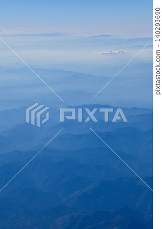 The view of the stunning landscape with mountains and clouds from the airplane window. Aerial view of the natural scene, mountain range. Travel and landscape scene. Travel and nature concept. The view of the stunning landscape with mountains and clouds from the airplane window. Aerial view of the natural scene, mountain range. Travel and landscape scene. Travel and nature concept. 140293690