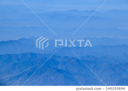 The view of the stunning landscape with mountains and clouds from the airplane window. Aerial view of the natural scene, mountain range. Travel and landscape scene. Travel and nature concept. The view of the stunning landscape with mountains and clouds from the airplane window. Aerial view of the natural scene, mountain range. Travel and landscape scene. Travel and nature concept. 140293694