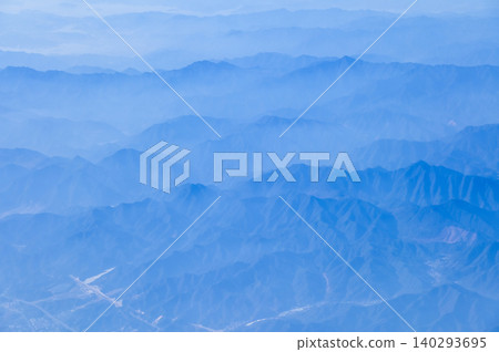 The view of the stunning landscape with mountains and clouds from the airplane window. Aerial view of the natural scene, mountain range. Travel and landscape scene. Travel and nature concept. The view of the stunning landscape with mountains and clouds from the airplane window. Aerial view of the natural scene, mountain range. Travel and landscape scene. Travel and nature concept. 140293695