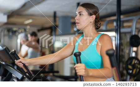 Sporty girl working out on elliptical machine in gym. Healthy active lifestyle concept Sporty girl working out on elliptical machine in gym. Healthy active lifestyle concept 140293713
