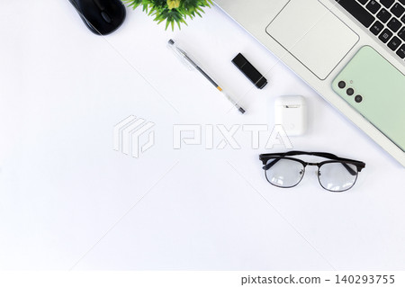 Clean desk with laptop, phone, glasses, and pen. White surface holds modern tech and accessories. Glasses sit beside keyboard, suggesting focus. Phone rests near plant, hinting at calm productivity Clean desk with laptop, phone, glasses, and pen. White surface holds modern tech and accessories. Glasses sit beside keyboard, suggesting focus. Phone rests near plant, hinting at calm productivity 140293755